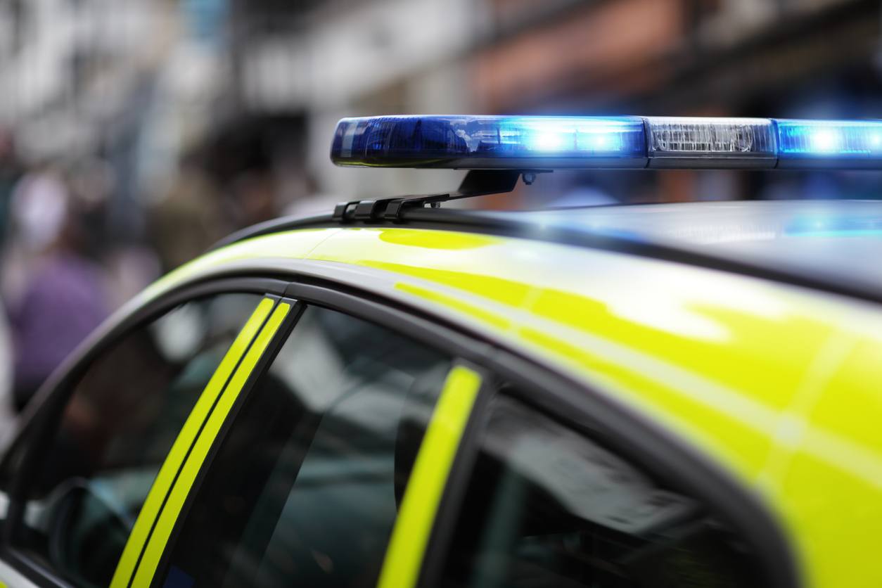 UK police car with flashing blue mergency lights on roof.