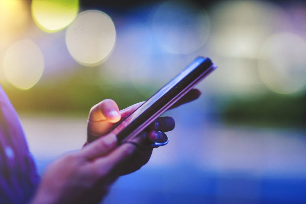 female hand using smartphone, night blur background